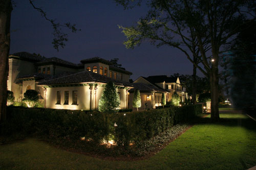 Popular Choices for Designing Electrical Service This Spring - A home's yard at night, with accent lighting for the walls and hedge