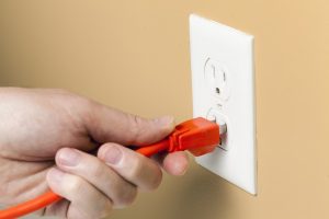 residential electrical wiring safety man-putting-a-plug into an electrical receptacle